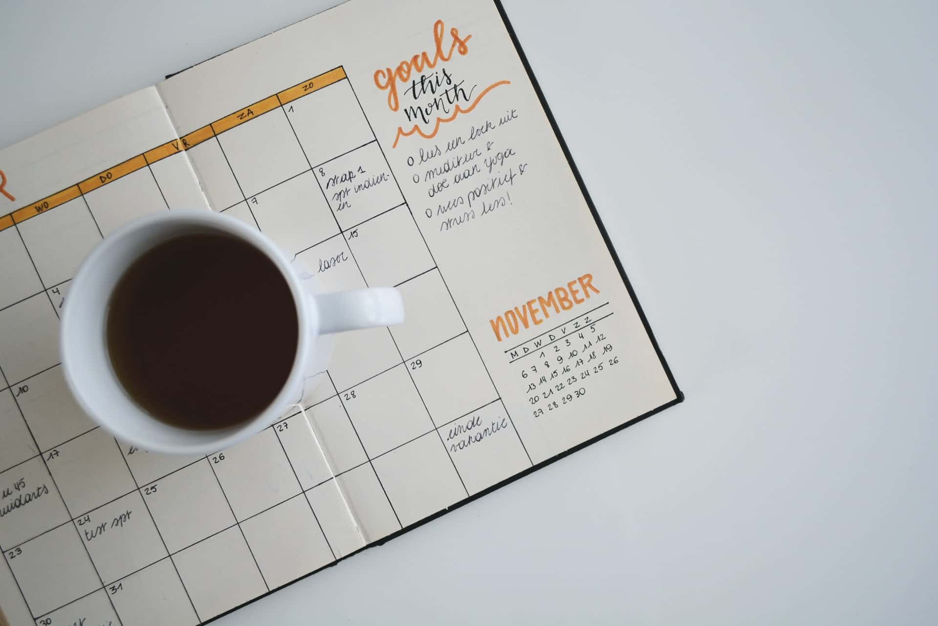Monthly planner and coffee mug on a desk